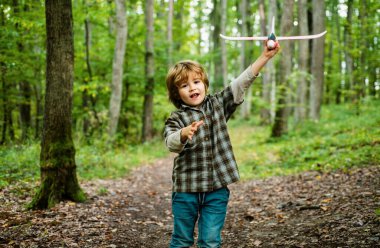 Oyuncak uçağı olan 6 yaşındaki çocuk yazın doğada seyahat etmeyi hayal ediyor. Çocuk rüyaları. Çocuk oyuncak bir uçakla oynuyor ve pilot olma hayali kuruyor.