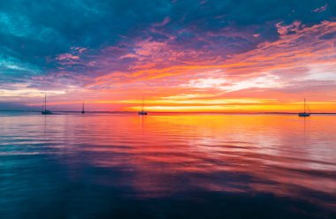 Gün batımında gökyüzü ve bulutların arasında güneş olan sakin bir deniz. Okyanus ve gökyüzü arkaplanı, deniz manzarası