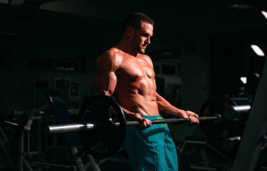 Formda bir adam. Çıplak gövdeli genç kaslı adam spor salonunda çalışıyor. Spor yapan atletik erkek sporcu. Spor konsepti.