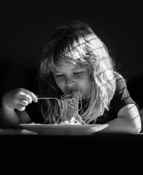 小孩子在厨房里吃意大利面 可爱的孩子自己用勺子吃饭 小孩在吃饭 特写小孩的脸 小孩儿吃面条面食的特写 — 图库照片