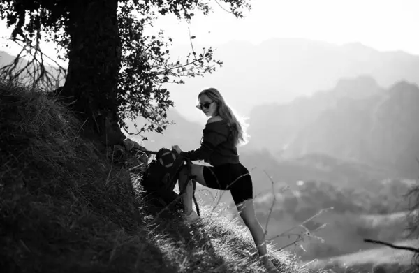 美しく野生の風景で丘を登るバックパック付きの女の子ハイカーハイキング 山の中で美しい若い女性 バックパッキング観光コンセプトの背景 — ストック写真