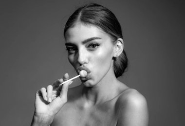 Kırmızı dudaklı, lolipop tutan seksi bir kadın. Güzellik abidesi. Stüdyoda şehvetli kadın portresi