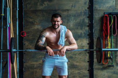 Muscular man workout in the gym. Athletic man having weight training in gym. Handsome man with strong muscles workout in the gym. Portrait of sexy muscular male with dumbbells. Bodybuilder exercise