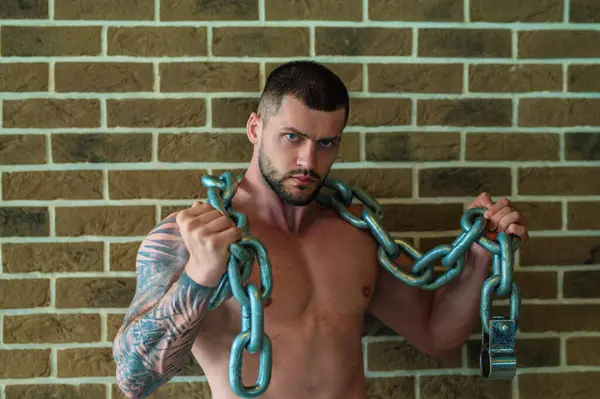 Man exercising with weight metal chains. Fit model lifting weight chains, workout at gym. Workout with chains. Man strong muscular fit man workout with chains with heavy weight. Exercises for biceps