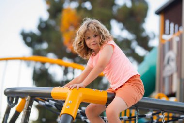 Sevimli çocuk oyun bahçesinde oynuyor. Çocuk parka tırmanıyor.