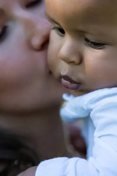 Mothers kiss. Close up portrait of mother kissing multiracial baby. Mother kiss Biracial child, macro. Closeup face of Mother with baby kissing outdoor. Tender moms kiss. Biracial baby and Mother kiss