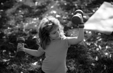 Çocuk kas geliştirmek için egzersiz yapıyor. Çocuk parkta dambıllarla egzersiz yapıyor.