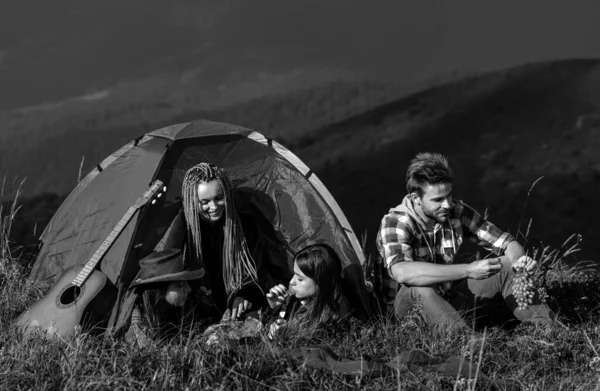 Young people on camping trip. Healthy lifestyle and eco tourism. Group of happy friends in tent eating summer fruits at camping