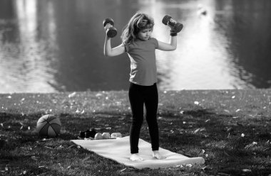 Arka bahçede dambılları kaldıran komik çocuk. Eğitimdeki çocuklar