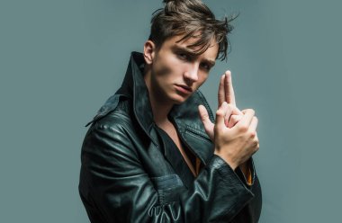 Gri arkaplan ve parmak tabancası jesti olan şık bir genç adam.