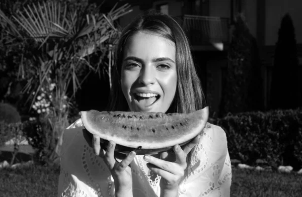 Closeup portrait of young sensual woman eating watermelon. Happy young woman with watermelon in park