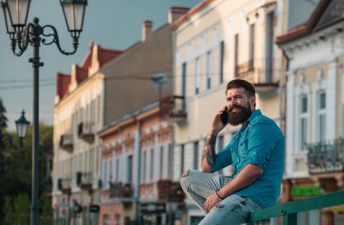 Dışarıda cep telefonuyla konuşan mutlu genç adam.