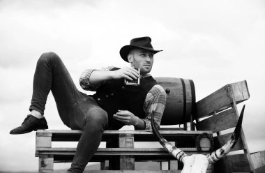 Çiftlikteki kovboy. Kovboy şapkalı ve antika kıyafetli yakışıklı bir adam. Viski ya da brendi ile çekici bir adam.