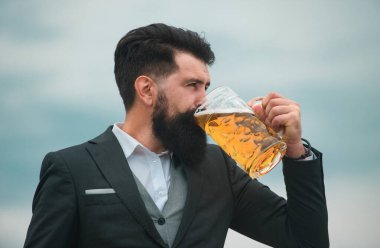 Sakallı barmenin profil portresi bira içiyor. Hippi adam bira içiyor.