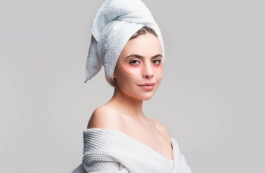 Göz bantlı güzel kadın mükemmel bir cilt etkisi gösteriyor. Gri stüdyoya izole edilmiş yüz bantlarına başvuran çekici genç bir kadının portresi.