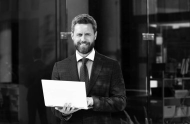 Dışarıda dizüstü bilgisayar kullanan yakışıklı iş adamının portresi.