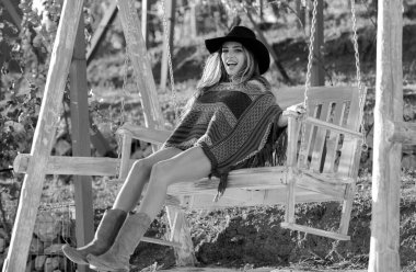 Parkta salıncakta sallanan boho tarzı genç bir kadın. Güzel hippi kadın bahçede salıncakta dinleniyor. Şapkalı şehvetli bir kızın yaz moda portresi. Gülümseyen mutlu bir kızın açık hava portresi