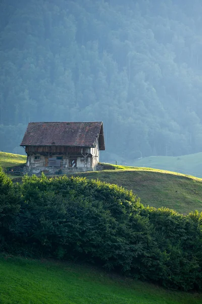 Alps house in mountains. Mountain green field alpine Mountains landscape nature with wooden old houses. Travel and hiking concept. Landscape with old buildings, high rocks. Mountains in Alps