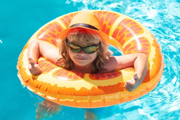 Güneş gözlüklü çocuk yaz günü havuzda. Çocuklar yüzme havuzunda oynuyor. Yaz tatili ve tatil konsepti
