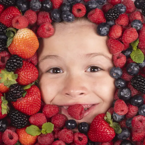 Summer fruits. Mix of berries. Kids face with fresh berries fruits. Assorted mix of berries strawberry, blueberry, raspberry, blackberry on background. Healthy nutrition berries for kids