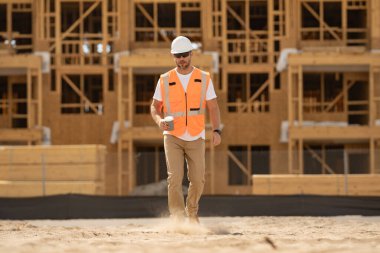 Binada miğferli beyaz adam inşaat işçisi. İnşaat binası. İnşaat alanı yöneticisi. Yeni binada miğferli bir işçi var. İnşaat alanında kasklı miğfer kullanan bir mimar.