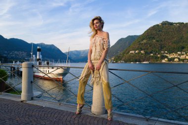 Moda kadını portresi Avrupa 'daki Como Gölü' nde poz veren genç ve modaya uygun bir kız. Yaz sokak modası. Yaz boyunca tatilin tadını çıkaran güzel genç bir kadın. Como Gölü İtalya 'da lüks seyahat