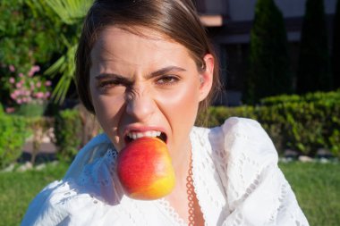 Stomatoloji konsepti. Dişlerinde elma olan kadın. Yeşil elmalı güzel bir kadının açık hava portresi. Sağlıklı diyet yemekleri. Elma yiyen komik bir kadın, sağlıklı bir yaşam tarzı. Sağlıklı dişler için meyve.