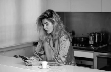 Sinirli ev hanımı mutfakta kahve içer. Sabahları mutfakta telefonda konuşan üzgün bir kadın.