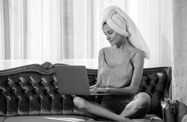 Genç bir kadın sabahları dizüstü bilgisayar kullanıyor. Kız bir sabah lüks yatak odasında dinleniyor ve rahat bir kanepede uzanıyor.