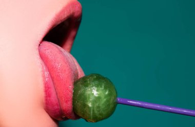 Cazibeli ağız kırmızı dudaklı lezzetli lolipopları yalıyor. Lolipop berbat. Seksi kadın dudağı. Lolipopu olan şehvetli, kırmızı dudaklı bir kadın. Çikolata konsepti