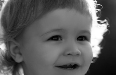 Neşeli çocuğun yakın plan portresi. Sevimli, neşeli, makro suratlı bir çocuk. Çocuklar gülümsüyor, sevimli bir gülümseme. Komik bir çocuğun açık havada çekilmiş portresi.