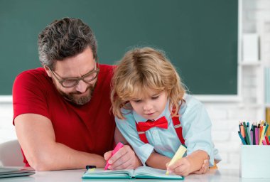 Öğretmen, ilkokuldan çocuk öğrenciye sınıfta yardım ediyor. Öğretmen ve çocuk okulda öğreniyor.