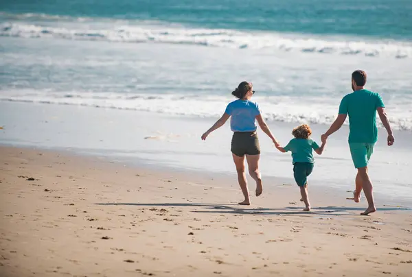Happy family running on beach at sunset. Family traveling concept. Healthy people
