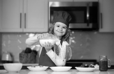 Şef çocuk malzemeleri hazırladı. Önlüklü aşçı çocuk ve mutfakta aşçı şapkası. Sağlıklı yemek.