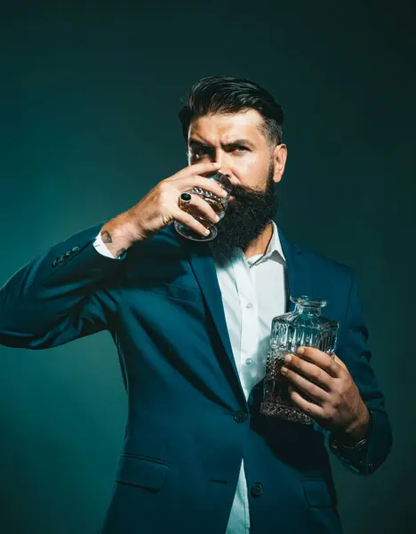 Fashion style concept. Man Bartender with beard holds glass brandy. Sommelier tastes expensive alcohol drink. Alcoholic beverage