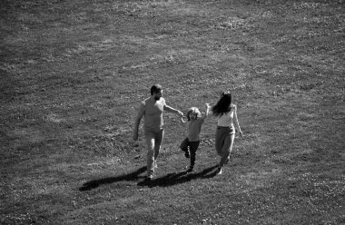 Baba, anne ve oğul parkta koşuyor. Aile hayatı olan güzel doğa manzarası.