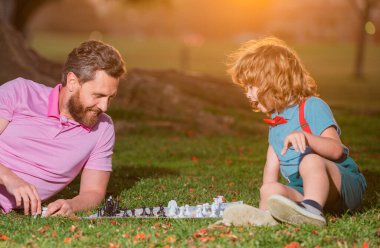 Baba ve oğul parkta birlikte satranç oynuyorlar. Aktif insanlar parkta satranç oynayıp eğleniyorlar, çocuklarla vakit geçiriyorlar.