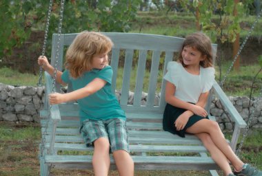 İki çocuk yaz parkında dinleniyor. Erkek ve kız kardeş mutlu bir şekilde doğada yürüyor. Kardeşler bahçede oynuyorlar.