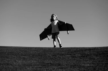 Sırt çantalı kanatlı çocuk gezgin. Pilot pilotçuluk oynayan ve dışarıda parkta rüya gören bir çocuk. Mutlu çocuk dışarıda oynuyor.