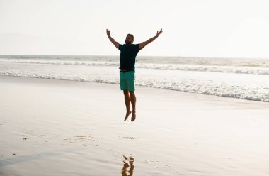 Kaygısız bir adam doğaya atlıyor. Sahile atlayan adam.