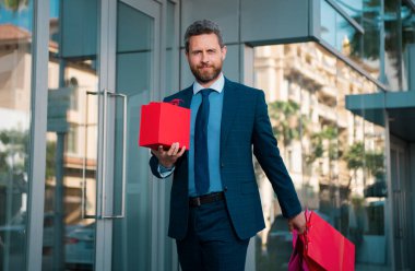 Harika bir hediye. Elinde hediye kutusu olan ve şehrin karşısında dururken gülümseyen adam