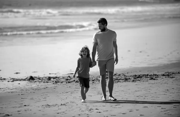 Father and son walking on summer beach. Childhood and parenting concept