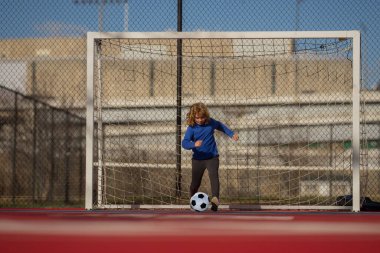 Çocuk futbolcu ya da futbol stadyumunda futbol topunu gol için tekmeleyen futbolcu. Spor anlayışı, rekabet. Çocuk futbol topunu tekmeliyor. Çocuk futbol topunu tekmeliyor. Çocuklar için spor
