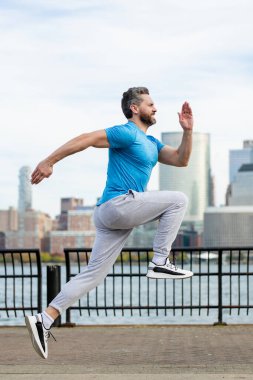 Kaçak. Sokakta koşan bir adam. Olgun koşucu ve spor modelleri New York 'ta Manhattan yakınlarında antrenman yapıyor. Milenyum sporcusu dışarıda spor yaparken koşuyor.