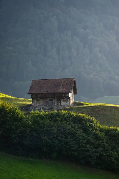 Alps house in mountains. Mountain green field alpine Mountains landscape nature with wooden old houses. Travel and hiking concept. Landscape with old buildings, high rocks. Mountains in Alps