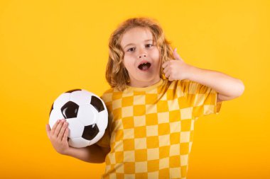 Futbol topu tutan, kameraya gülümseyen, futbol oynayan, stüdyoda oynayan bir çocuk. Spor ve eğlence, çocuklar için futbol hobisi. Futbol topu tutan küçük çocuk. Futbol topu olan fanatik sporcu çocuk.