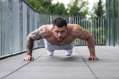 Sexy muscular man pumps his muscles and lifts dumbbells in gym. Strong fit man exercising with dumbbells. Muscular young handsome man lifting weights. Weightlifting and training with dumbbells
