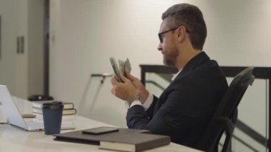 Ofiste parası olan heyecanlı bir iş adamı. Paralı takım elbiseli zengin bir adam. Başarılı bir iş adamı dolar banknotlarını elinde tutar. Takım elbiseli zengin yönetici para sayıyor. Bütçe, ödeme faturaları, mali planlama