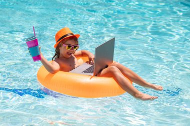 Yaz havuzunda dizüstü bilgisayarı olan bir çocuk. Su geçirmez laptop