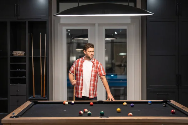 The billiard. Guy Playing billiards. Man hit ball in billiard in Billiard room. Russian pool billiards. Snooker Player. Young professional man playing billiards in the dark billiard club